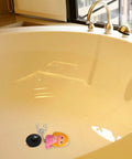 Mermaid Bathtub Stopper Plug Rubber Drain Seal with Chain resting in a beige bathtub, featuring a pink mermaid design and shiny chain.