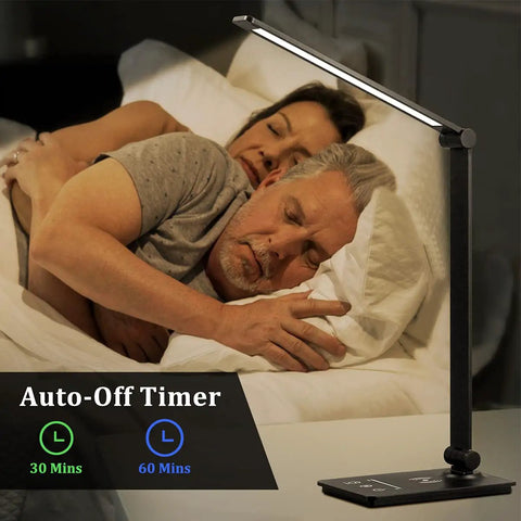 Lit LED Desk Lamp With Wireless Charger For Dorms And Office, 5 Color Modes And Full Dimming beside a sleeping couple