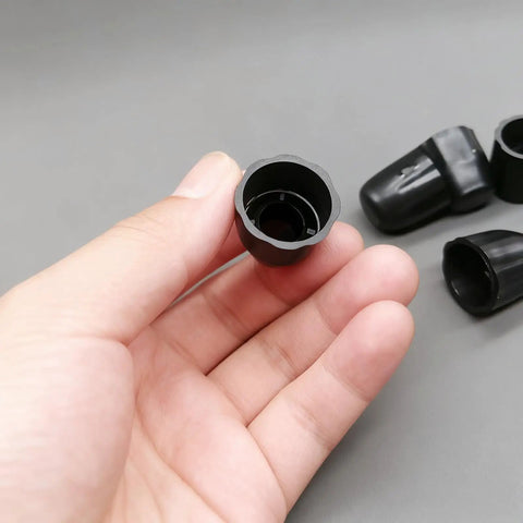 Hand holding one black piece from 8 Pack Bicycle Axle Dust Cover Replacement Set, Durable Black Plastic Axle Caps For Bike Wheel Hubs