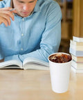 Person reading with 180 Pack 16 Oz Disposable Coffee Cups White Paper Cups For Hot Or Cold Beverages Water Juice Or Tea Sturdy Anti Leak