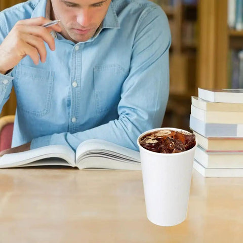 Person reading with 180 Pack 16 Oz Disposable Coffee Cups White Paper Cups For Hot Or Cold Beverages Water Juice Or Tea Sturdy Anti Leak