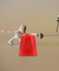Red cap next to fencing figurines on a table surface, associated with beefy stainless steel threaded nut replacement.