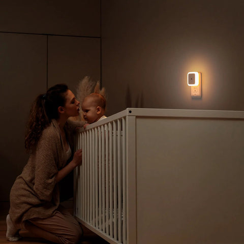 Sujeet night light; white plug-in wall LED emitting warm white glow above a baby's crib.