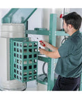 Man adjusting the filter of a 2 Horsepower Dual Filtration HEPA Cyclone Dust Collector in a workshop setting.