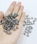 Hand holding 100 Pcs Dope Tiny Turtle Beads Antique Silver 0.9x0.7cm Mini Turtle Shaped Metal Beads For Crafts Jewelry Making
