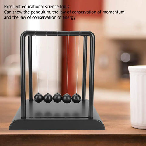 "Newtons Cradle Pendulum Desk Toy For Home Office Decor A Real Classic Nerdy Yet Cool Science Showpiece With Durable Steel Balls And Plastic Frame An Educational Physics Toy For Kids And Adults 17.8 x 14.8 x 18 cm placed on a wooden desk against a blurred background."