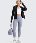 Person wearing Cozy Womens Fleece Full Zip Hoodie With Thumb Holes Black Hip Length Go To Casual Sweatshirt Jacket, leggings, holding bag.