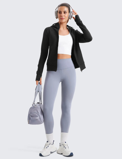 Person wearing Cozy Womens Fleece Full Zip Hoodie With Thumb Holes Black Hip Length Go To Casual Sweatshirt Jacket, leggings, holding bag.