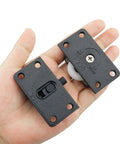 Person holding two sets black sliding cabinet hardware components with nylon pulley wheels, hand showing size and design details.