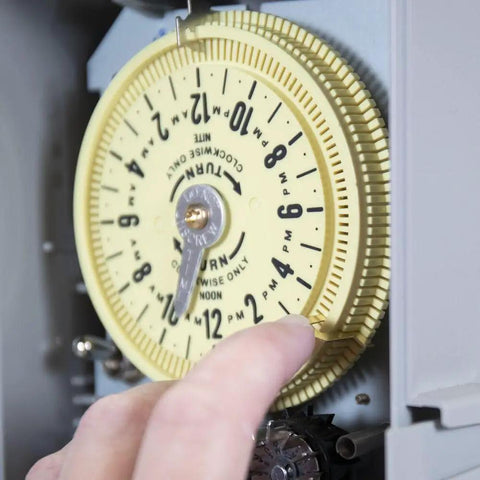 Close-up view of a hand adjusting the dial of 14 Day Skipper Sprinkler Timer With Customizable Water Conservation And Rain Ready Design