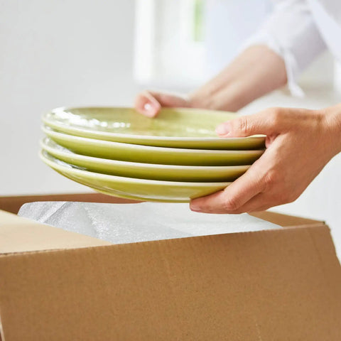 Person packing plates with Foam Wrap Roll 320 Ft By 12 In Thick 1/16 Inch Perforated Every 12 Inches for protection in a box.