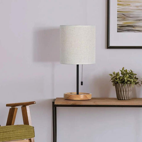 Modern Wood Base Table Lamp With Linen Shade For Nightstand And Desk Bedside Light For Living Room Bedroom Office Or Dorm Soft Non Flicker Glow That Eases Eyes And Creates A Cozy Vibe on a wooden table next to a plant and chair.
