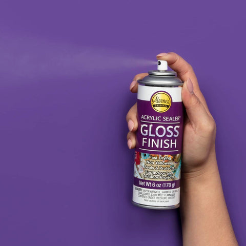 Hand holding Spray Gloss Finish Acrylic Sealer 6 Oz Clear Coat for DIY Indoor and Outdoor Projects, durable protective gloss can