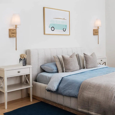 Sleek Modern Wall Sconces in Antique Brass Brush Finish With White Fabric Shade above bed in bedroom