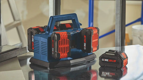 Ultra Fast 18V 6-Bay Battery Charger With 8 Amp Charge Delivers 80 Percent In 32 Minutes And 100 Percent In 50 Minutes, Sequentially Powers Six 18V Batteries For Back-To-Back Jobs, shown on workshop table with batteries