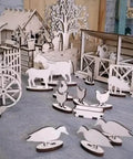 Laser-cut Baltic birch plywood farm animal shapes in natural wood on a workshop surface.