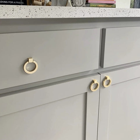 6 Pcs Brushed Brass Cabinet Ring Pulls Set In Zinc Alloy With Durable Single Hole Design installed on gray kitchen cabinets.