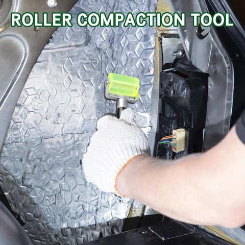 Front view of a gloved hand using a green seam roller on automotive PU sound-deadening mat inside a car.