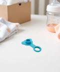 Blue Silicone Bathtub Plug Stopper for 1 Inch Drains on a tabletop with baby items in the background.