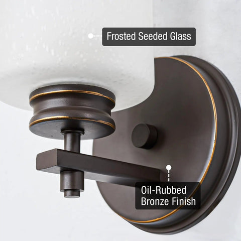 Close-up of Phoebe 8 Inch Modern Wall Sconce with Frosted Seeded Glass Cylinder Shade in Oil Rubbed Bronze Finish.