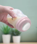 Hand holding bottle with pink Travel Caps With Rewritable Sealing Disc For Avent Wide Mouth Bottles, Leak Resistant Screw Lids