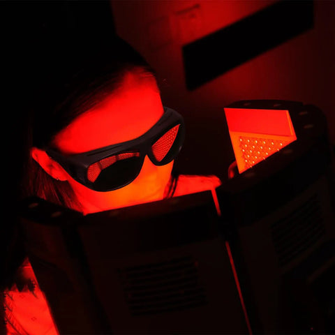 Person wearing Laser Safety Glasses With Green Absorption Lens For Engravers And Cutters engaged in studio work with red light exposure
