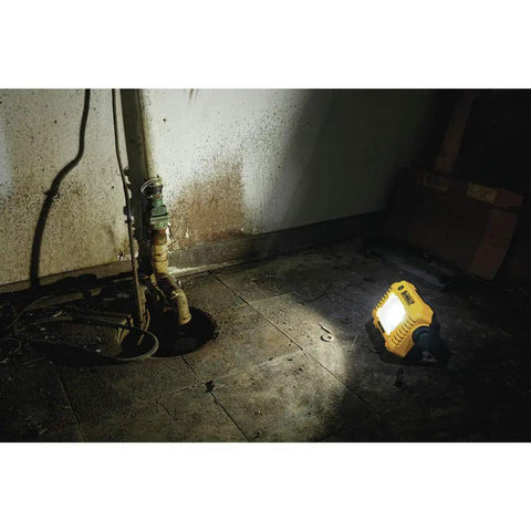Powerful 2000 Lumen LED Work Light illuminating a dark basement with 360 degree rotating handle, cordless bare tool setup visible