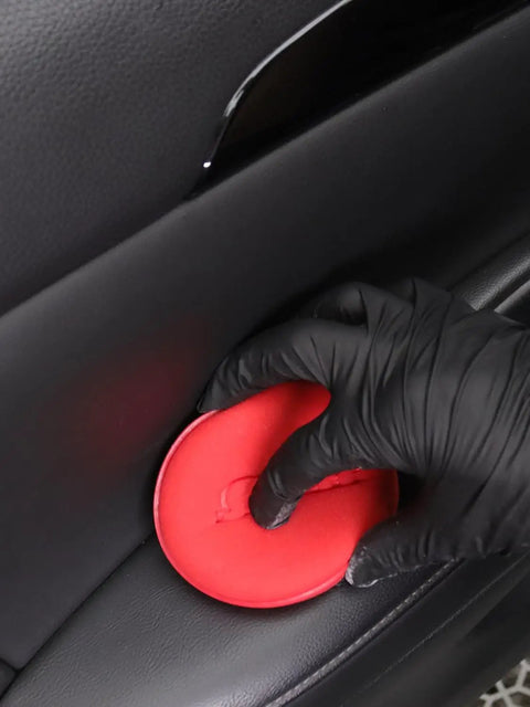 Gloved hand using red foam pad from 10 Pack Foam Wax Applicator Pads For Car Detailing on leather interior