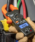 Close-up of Digital Clamp Meter with Auto-Ranging 400 Amp AC in use on job site, showing backlit LCD and clamp on wire