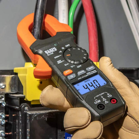 Close-up of Digital Clamp Meter with Auto-Ranging 400 Amp AC in use on job site, showing backlit LCD and clamp on wire