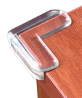 Clear Corner Guards 12 Pack for baby proofing tables and furniture showing ultra strong adhesive gel edge bumper on wooden table corner.