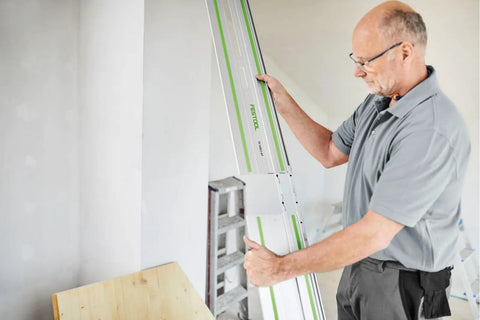 Man aligning Guide Rail Connector Set FSV2 for long workpieces with auto alignment, showcasing a two-piece joint and laser markings.