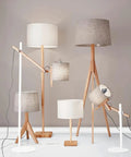 Collection of various lamps with natural wood bases and felt shades in a living space setting.