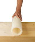 Person unrolling Silicone Glue Mat XXL For Workbench 23.5 By 60 Inches Easy Clean Craft Surface on wooden table.