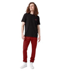 Men's Skinny Straight Double Knee Work Pants With Heavy Duty Reinforcement, Wrinkle Resistant Fabric, And A Stain Release Finish That Looks Sharp On The Job Site All Day In English Red worn with a black t-shirt and white sneakers.