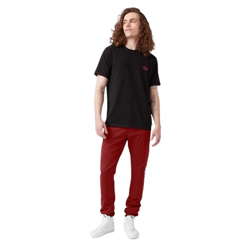Men's Skinny Straight Double Knee Work Pants With Heavy Duty Reinforcement, Wrinkle Resistant Fabric, And A Stain Release Finish That Looks Sharp On The Job Site All Day In English Red worn with a black t-shirt and white sneakers.