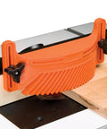 Bully Proof Arched Featherboard For Router Table Fences Tight Space Friendly Setup, orange plastic tool securing wood, ensuring precise cuts.
