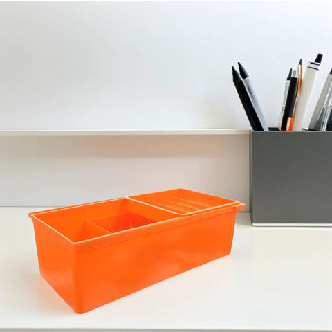 Orange plastic desk storage drawer box with tier compartments next to pens, for under desk organization large capacity desktop organizer