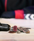 Drill with 40 Piece Abrasive Buffing Wheel Set for metal and plastic, polishing coins on a wooden surface.