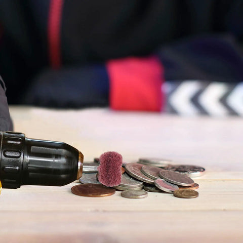 Drill with 40 Piece Abrasive Buffing Wheel Set for metal and plastic, polishing coins on a wooden surface.