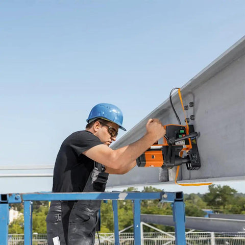 Heavy Duty Magnetic Base Drill Built Tough For One Quarter Inch Steel Cuts used by a worker on a steel beam at a construction site.