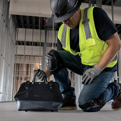 Worker kneels on site with Heavy Duty Black Canvas Tool Bag With Wide Mouth Opening Leather Handles 12 Inch Tool Tote