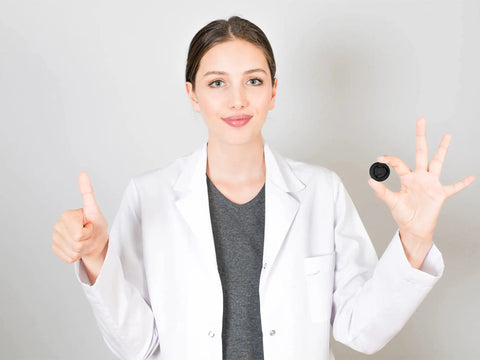 Young woman in a lab coat showing a black latex finger cot, promoting Ace Every Shift With This 400 Pack Black Latex Finger Cots Kit.