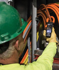 Electrician using Digital Clamp Meter With Auto Range TRMS For AC DC Voltage And Current Up To 2000A in industrial setting