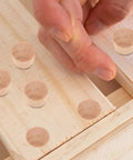 Close-up of hand placing khaki wood cabinet hole plugs for DIY projects and furniture finishing, eco-friendly reusable design