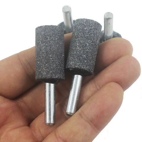 Hand holding 16mm Cylindrical Grinding Stones With 1/4 Inch Shank Pack Of 8 Aluminum Oxide Mounted Grinding Bits for rotary tools.