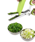 Green-handled 5-blade herb scissors cutting chopped herbs; stainless blades beside bowls of diced onions and greens.