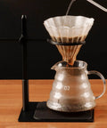 Adjustable Pour Over Coffee Stand Featuring Rock Solid Aluminum Base For Home Office Brewing with coffee dripping into glass pitcher.