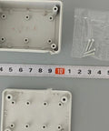 Durable White Plastic Junction Box for Organizing Cables with screws beside measuring tape for size reference.