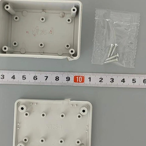 Durable White Plastic Junction Box for Organizing Cables with screws beside measuring tape for size reference.